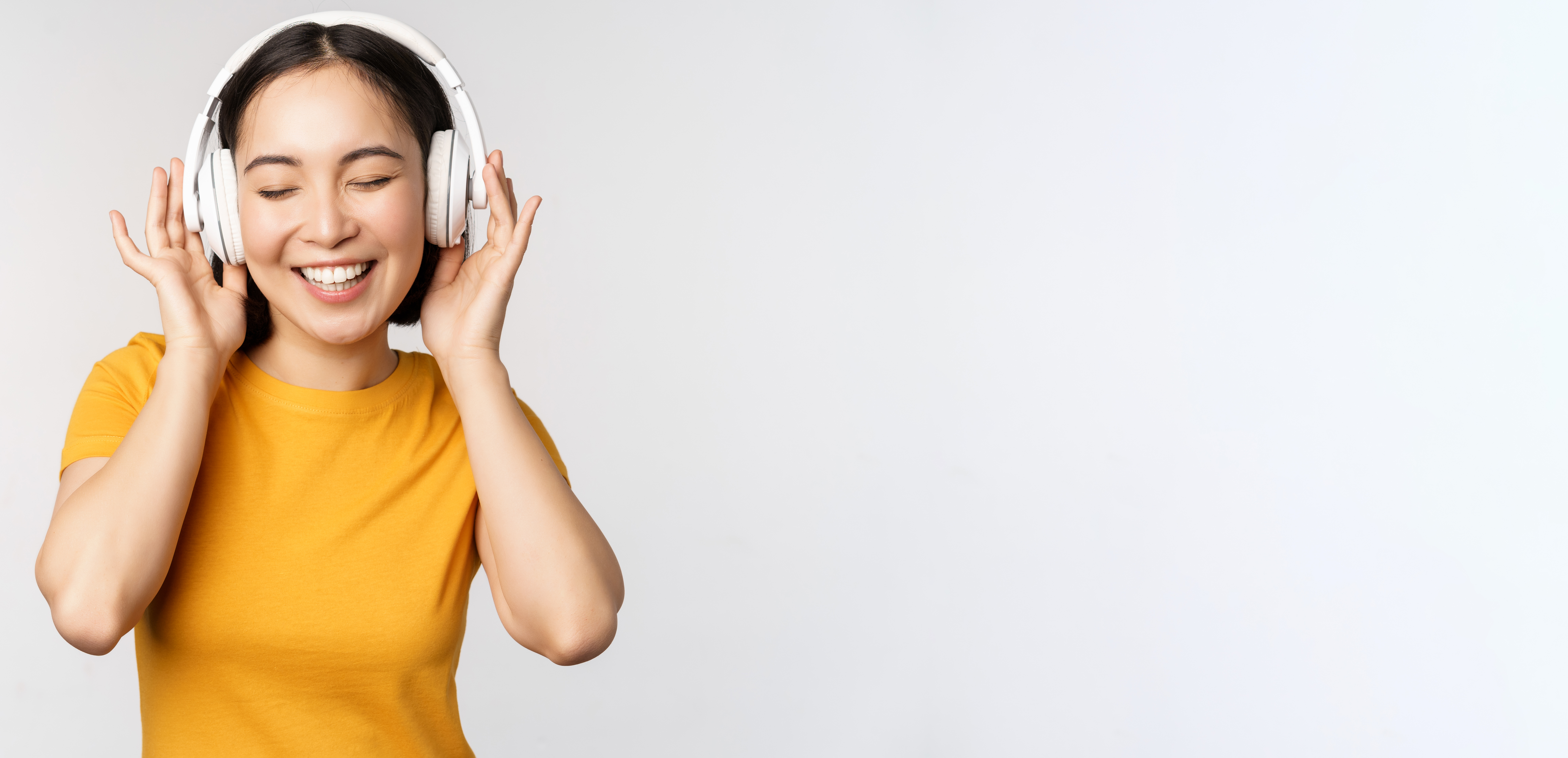 Copy-of-happy-asian-girl-dancing-listening-music-headphones-smiling-standing-yellow-tshirt-against.jpg